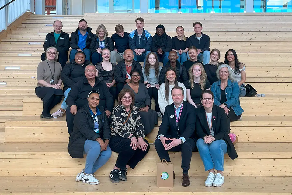 En grupp människor sittandes i en stora trappa på Dragonskolan i Umeå.