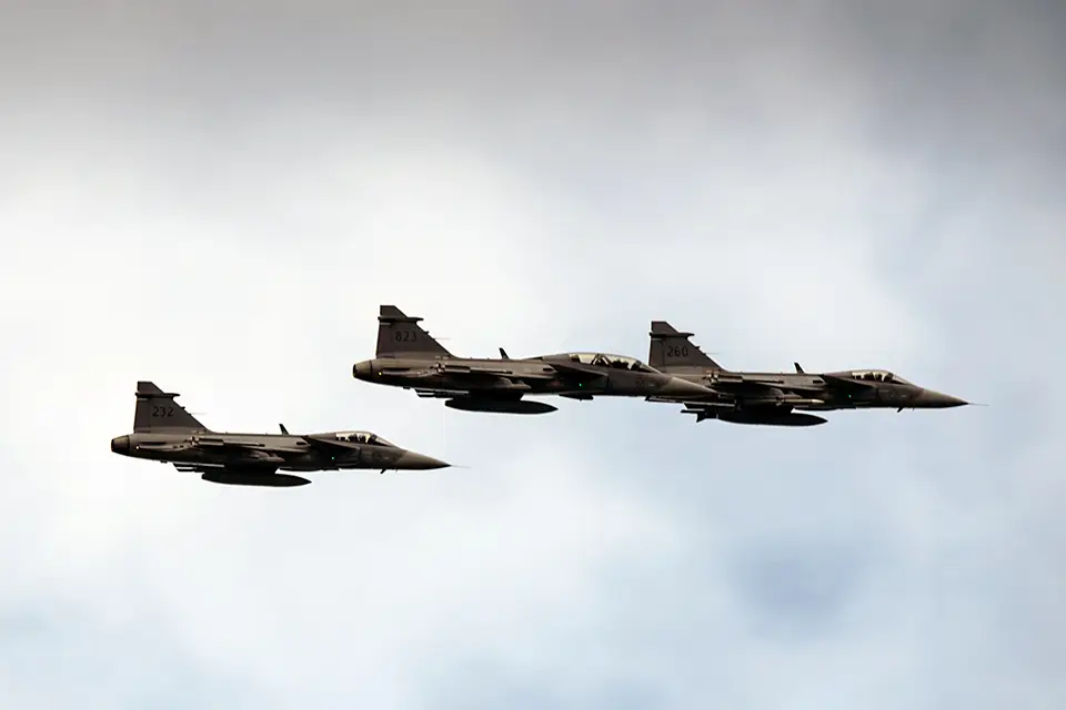 En grupp JAS 39 Gripen-flygplan i luften mot en grå himmel
